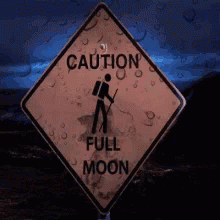 the blue sign has writing underneath it that says caution full moon