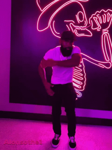 a man is standing in front of a colorful neon sign