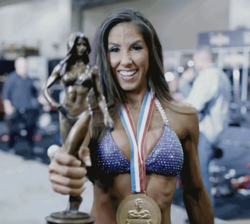 a woman in a bikini holds up a bronze medal