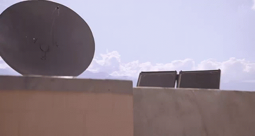 a satellite dish sitting on top of a cement block wall