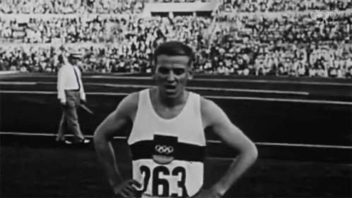 the olympic winner stands on a track surrounded by people