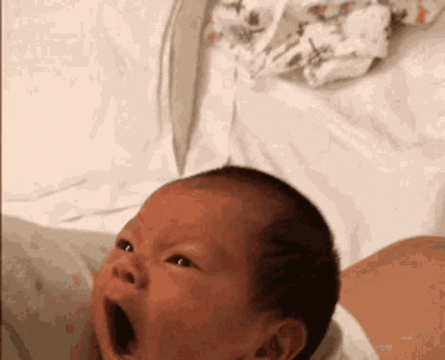 a baby holding it's mouth wide open while laying in bed