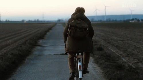 a person on a bicycle riding through a dirt road