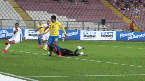 a soccer player falls onto the ground after kicking the ball towards him