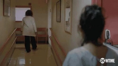 woman walking down the hallway of a hospital with medical equipment