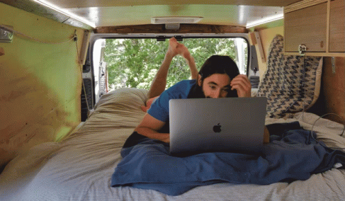 a woman using her laptop while lying in bed