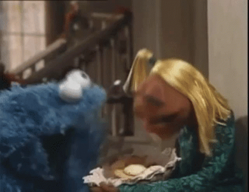 a stuffed animal with blue hair sits next to a teddy bear