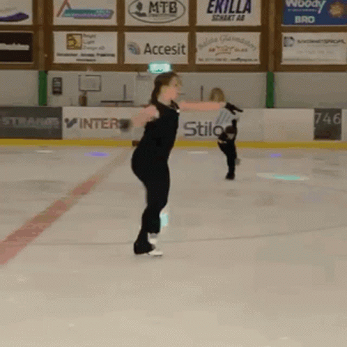 two people skating in an ice rink, one doing tricks