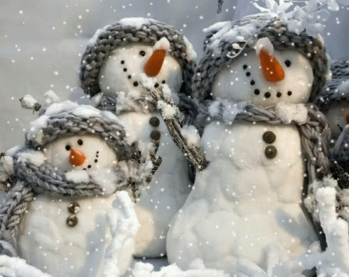 some very cute little snowmen by some bushes