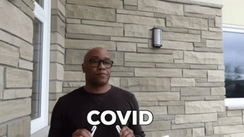 a man with the words covidd on his shirt in front of a brick wall