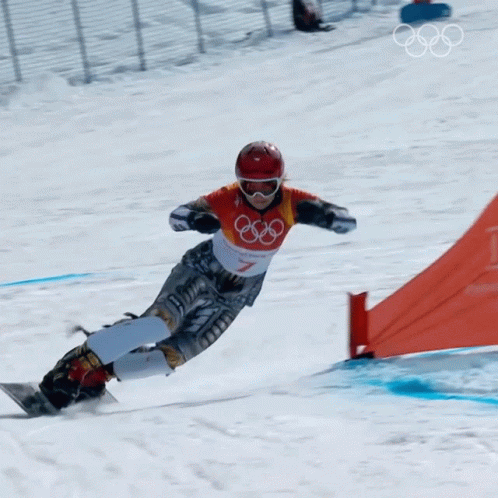 a person snowboarding down a snowy hill, with a fence in the background