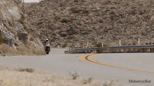 two motorcyclists on the road in front of mountains