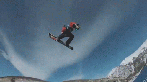 the snowboarder is airborne in a mountainous area