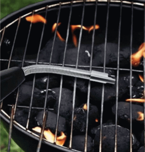 a grill is cooking black doughnuts with blue flame