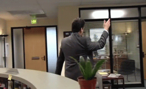 a man in a suit waves to an office