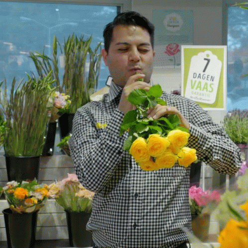 a man is in an outdoor flower shop holding fake flowers