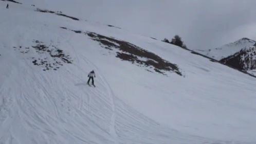 a couple of skiers are skiing down a large snowy hill