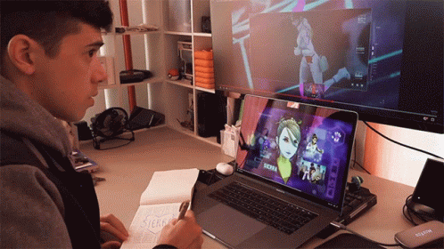 a young man playing on a computer with anime characters on it