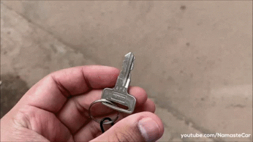a person holding onto a silver keys to a car