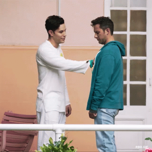 two men shake hands in front of a blue wall