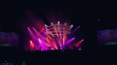 purple lights illuminate large crown on stage at a concert