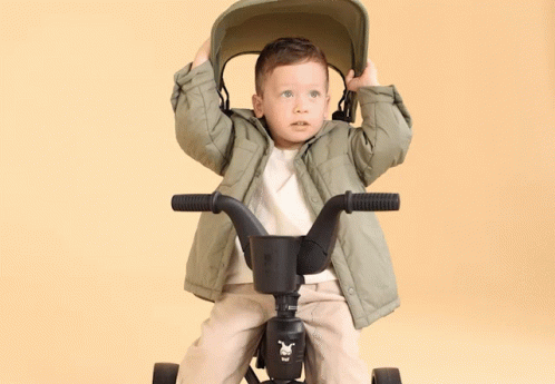 a small child is holding his head above his head on the handlebars of a bike