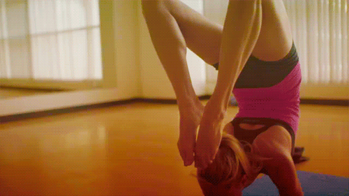a woman doing a handstand in a yoga studio