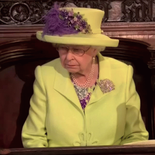 the queen of england, wearing an aqua green suit and matching hat with beaded ons