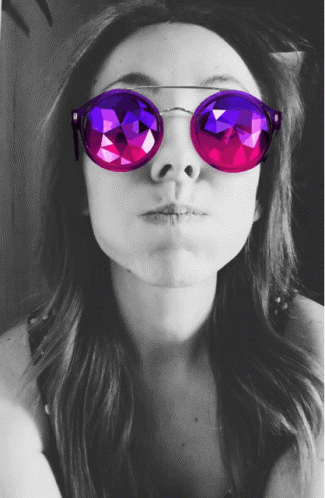 a woman with pink and purple sunglasses is posing for the camera