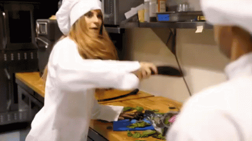 two people dressed in white clothing and blue makeup in a kitchen