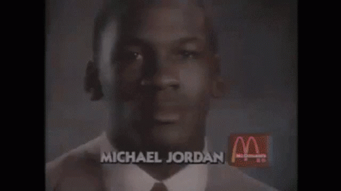 an african american man wearing a black tie in front of mcdonalds advertit