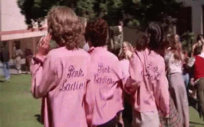 three women wearing pink shirts and jeans walking