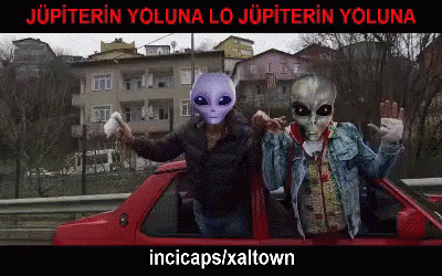 two alien figurines on a car next to an alien man