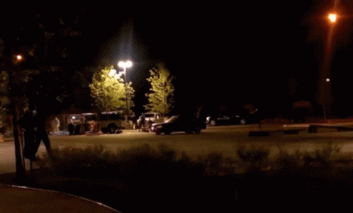 two cars are parked in a parking lot on the side of a road at night
