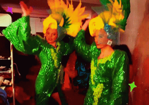 two dancers in green and blue outfits on a stage