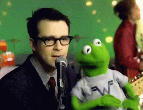 a man with glasses and a microphone talking to a puppet