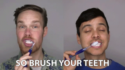 two men with blue and white face paint, both brushing their teeth