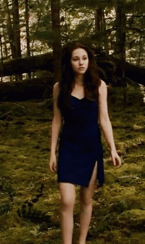woman in black dress standing in a wooded area