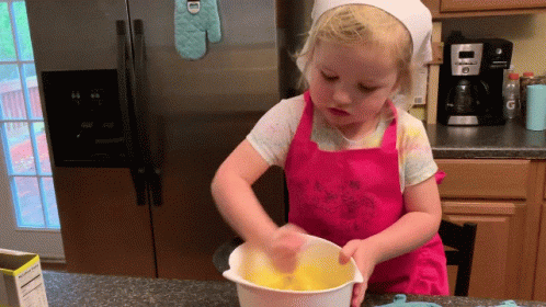 a little girl is mixing some kind of food