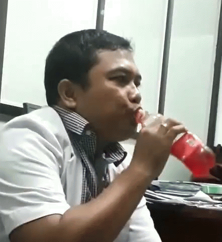 a man drinks water from a blue bottle