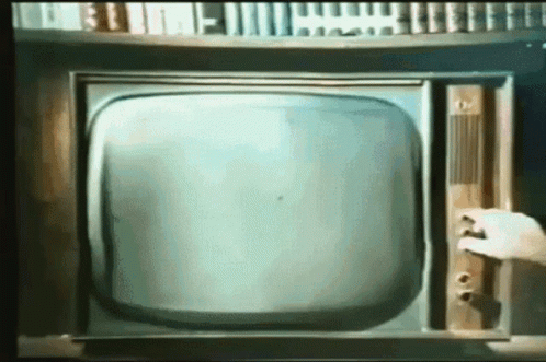 a man placing a on on a very old fashioned television