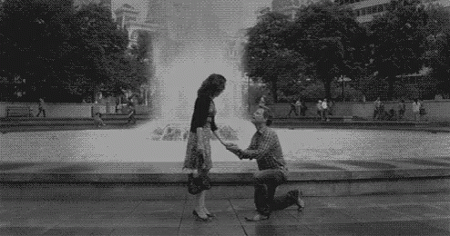 a man and woman shaking hands in front of a fountain