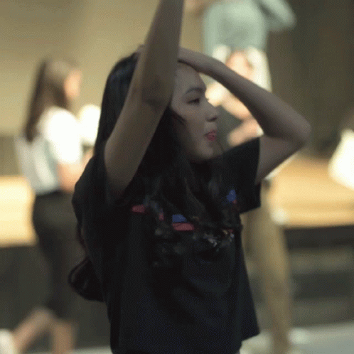 the girl is dancing while she puts her hands in her head