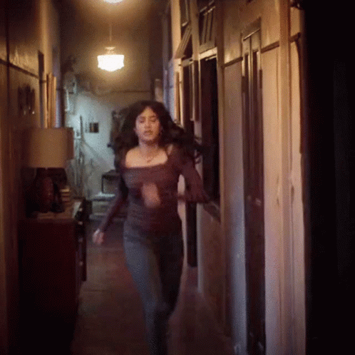 woman with y skin walking down hallway at night