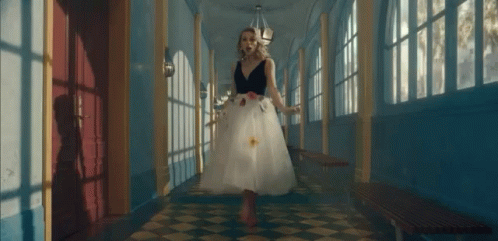 a girl in an odd dress standing in a hallway