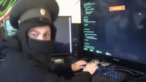 a computer user dressed in a hooded garb using two monitors