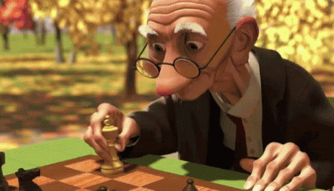 an elderly man plays chess in front of a group of people
