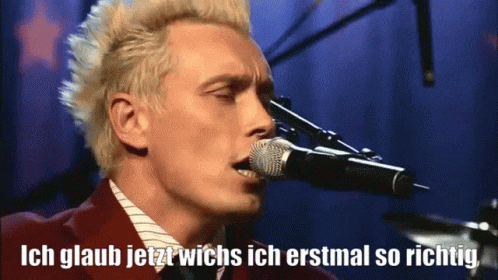 a man singing into a microphone with white hair