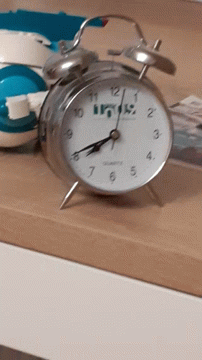 an alarm clock with a lamp sitting next to it on top of a blue table