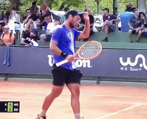a man in red shirt and black shorts playing tennis